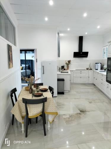 une cuisine blanche avec une table et des chaises dans l'établissement IMHOST - Spacious Appt near PARIS, à Pantin