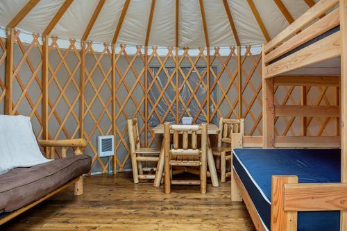 Long beach Camping Resort Yurt 9 في Oceanview: غرفة مع سرير وطاولة في يورت