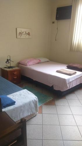 a bedroom with two beds and a table and a window at 4 suítes privativas in Santos
