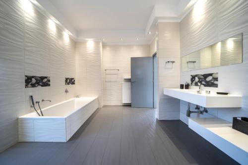 La salle de bains blanche est pourvue de 2 lavabos, d'une baignoire et d'une baignoire. dans l'établissement La Maison Du Soleil, à Varípetron