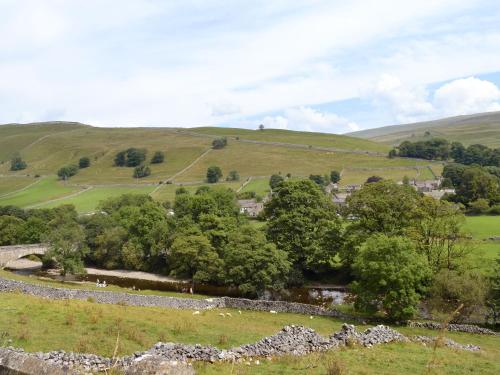 a view of a field with trees and a stone wall at Halton Gill Cottage in Deepdale