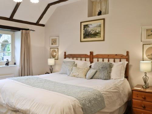 a bedroom with a bed with white sheets and pillows at Bakery Cottage in Ampney Crucis