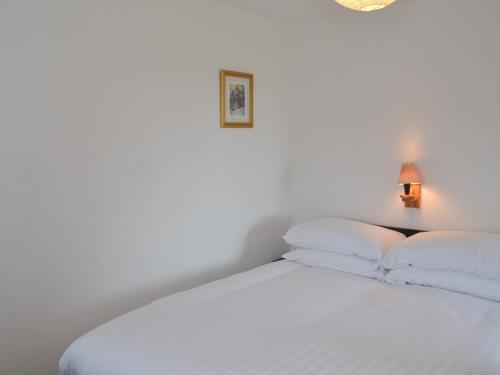 a bed with white sheets and pillows in a room at Copper Tree Cottage in Stokeinteignhead