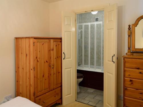 a bathroom with a toilet and a wooden cabinet at Freesia Cottage-mjd in Akeld