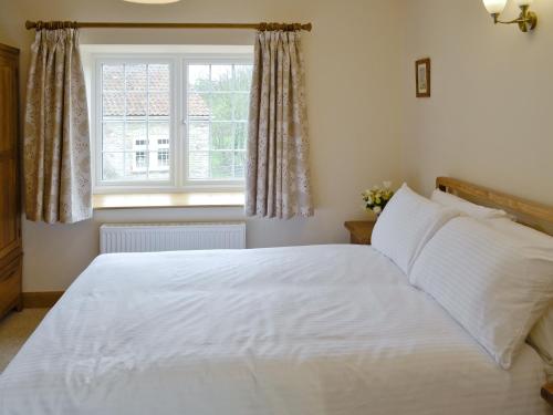 a bedroom with a white bed and a window at Dippers Folly in Buckland Dinham