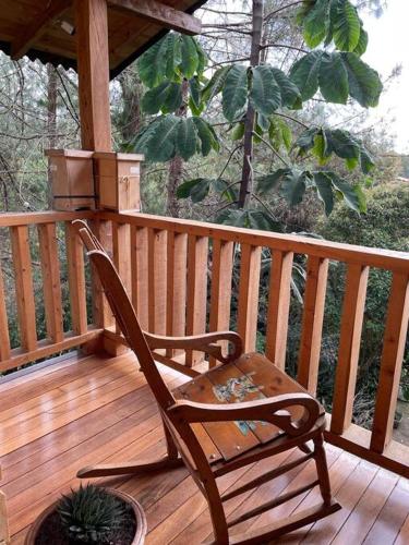 a rocking chair sitting on a wooden deck at Beehouse Arví Cabaña in Guarne