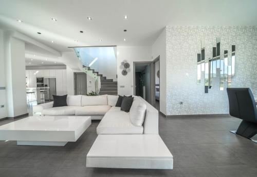 a living room with a white couch and a tv at La Maison Du Soleil Luxury Villa by 8essentially in Varípetron