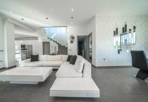 uma sala de estar com um sofá branco e uma televisão em La Maison Du Soleil em Varípetron