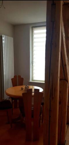 ein Esszimmer mit einem Tisch, Stühlen und einem Fenster in der Unterkunft Wohnen im Dreiseitenhof mit Galerieschlafzimmer in Neudietendorf