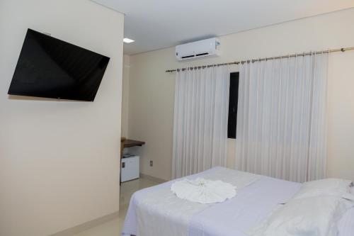 a bedroom with a white bed and a flat screen tv at Hotel Itatiaia in Tangara da Serra