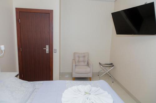 a bedroom with a bed and a chair and a television at Hotel Itatiaia in Tangara da Serra