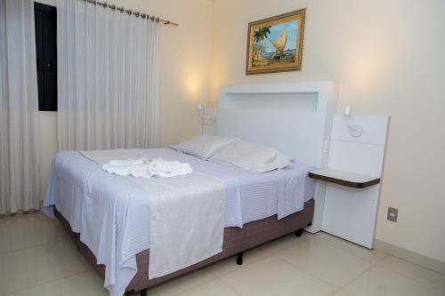 a bedroom with a bed with a white blanket at Hotel Itatiaia in Tangara da Serra