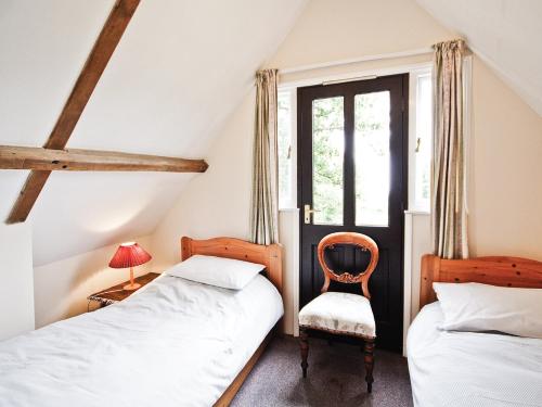 two beds in a room with a chair and a window at The Granary - E3669 in Saxtead