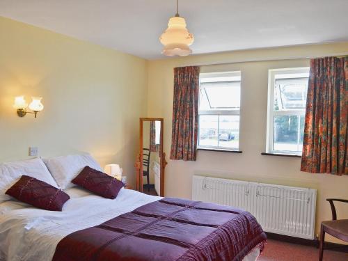 1 dormitorio con 1 cama y 2 ventanas en Murton Farm Cottage en Bishopston