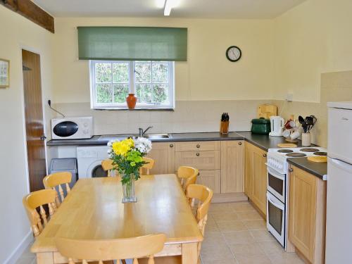 una cocina con una mesa de madera con un jarrón de flores. en Granary Cottage - E5634, en Warkleigh