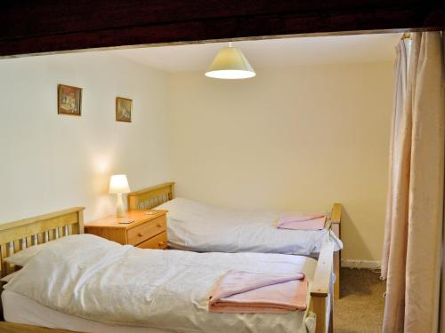 1 dormitorio con 2 camas, escritorio y lámpara en Granary Cottage - E5634, en Warkleigh