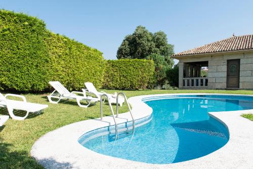 - une piscine avec des chaises longues à côté d'une maison dans l'établissement Villa Campo Das Medas , en medio de la naturaleza con piscina privada de sal, à Gondomar