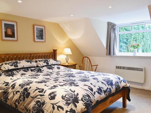 um quarto com uma cama e uma janela em Longcroft Cottage - 28233 em Old Rayne