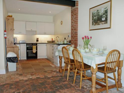 a kitchen with a table and chairs in a kitchen at The Coach House in Yaxham