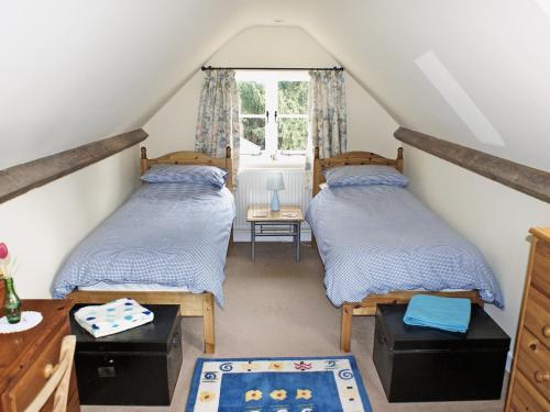 two beds in a attic room with a window at The Coach House in Yaxham