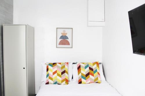 a white bedroom with a bed with colorful pillows at Practical Studio, Great Location, Parking, Netflix in Belvedere