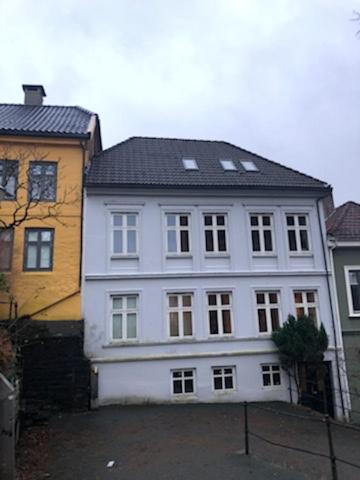 een groot wit huis met een zwart dak bij Fløyen Apartment in Bergen