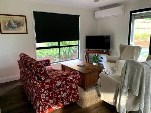 - un salon avec un canapé, des chaises et une télévision dans l'établissement Fig Street Cottage, à Maleny