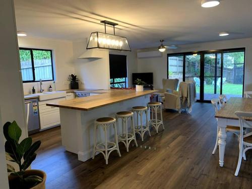 une cuisine avec un grand îlot et des tabourets de bar dans l'établissement Fig Street Cottage, à Maleny