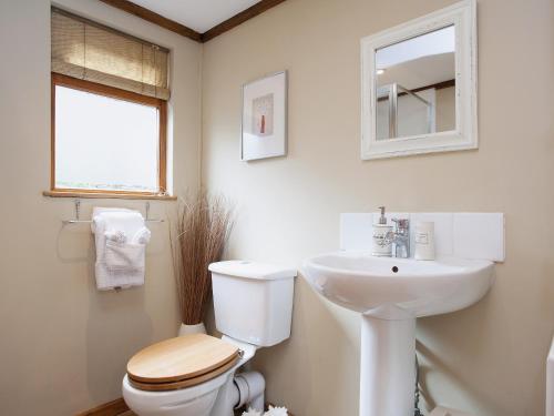 a white bathroom with a toilet and a sink at The Barn in Burley