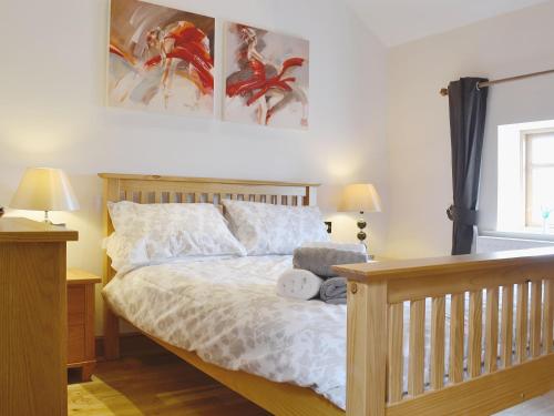 a bedroom with a bed and two pictures on the wall at The Top Barn in Coedana