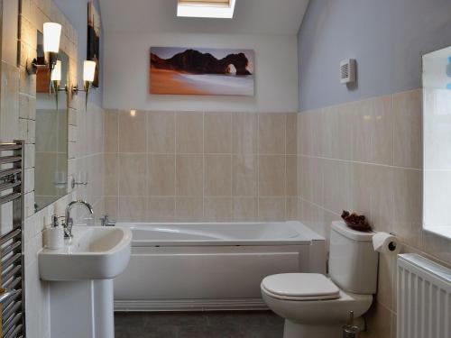 a bathroom with a tub and a toilet and a sink at The Top Barn in Coedana