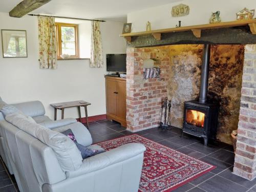 sala de estar con 2 sofás y chimenea en Strawberie Cottage - E2390, en Stoke Abbott