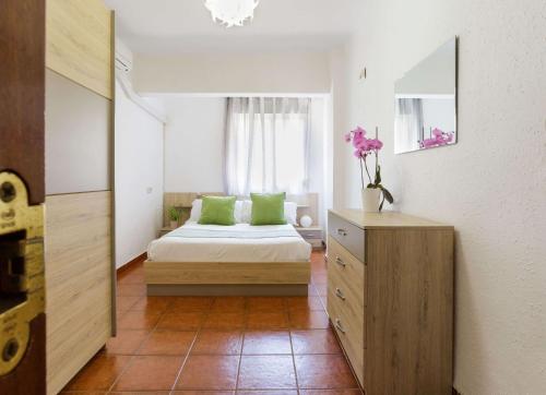a bedroom with a bed and a dresser and a mirror at Luchana Apartment in Málaga