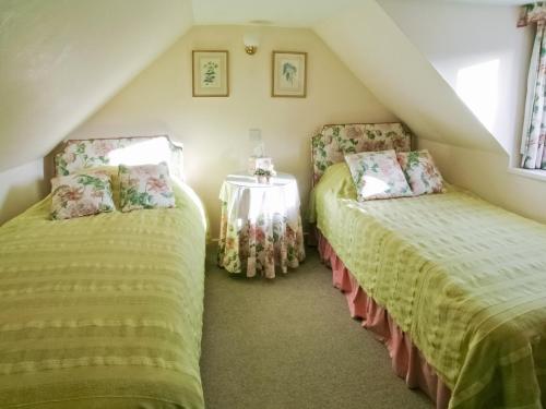 a attic room with two beds and a table at Wester Croachy Cottage in Aberarder