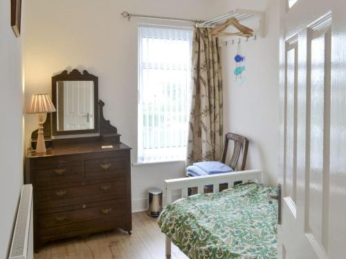 um quarto com uma cama, uma cómoda e um espelho em Dolphin Cottage em Newbiggin-by-the-Sea