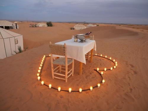 une table au milieu du désert avec des lumières dans l'établissement Royal Luxury Camp, à Merzouga
