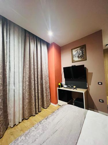 a bedroom with a bed and a desk with a television at Colombia Apartments&Rooms in Durrës