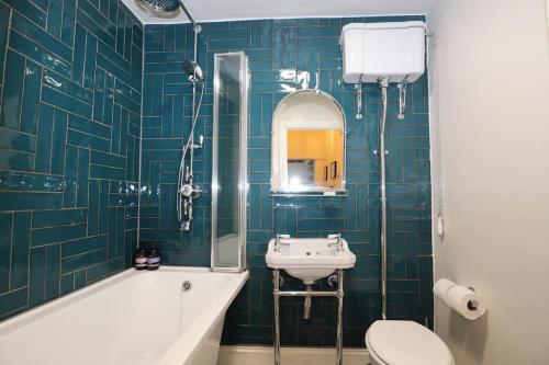 a bathroom with a sink and a toilet and a tub at Seagulls Nest- stylish 1 bed seafront apartment in Hastings