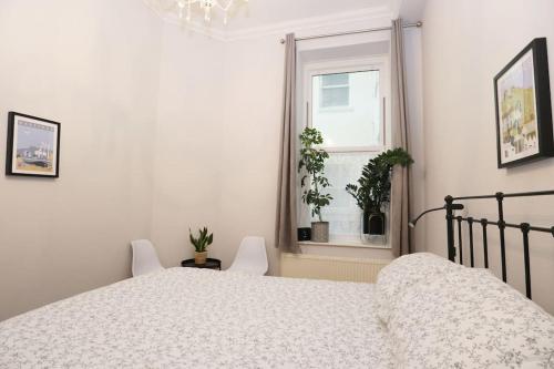 a white bedroom with a bed and a window at Seagulls Nest- stylish 1 bed seafront apartment in Hastings