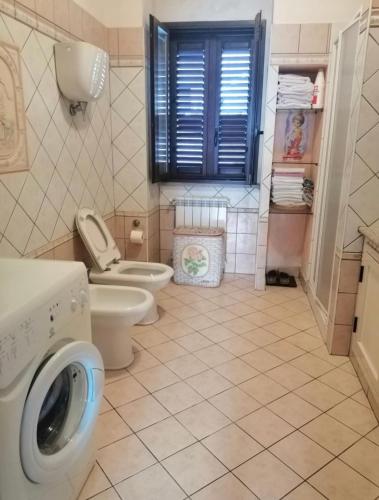 y baño con lavadora y aseo. en Bilocale nei pressi di Tropea en San Calogero