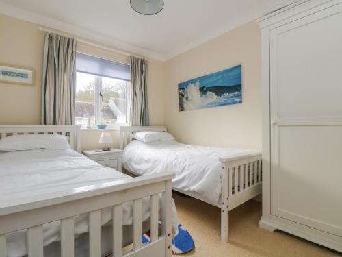 a bedroom with two beds and a window at Oyster Cottage in Falmouth