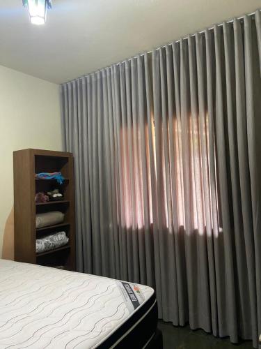 a bedroom with a bed and a window with curtains at Pousada Canto Feliz in Serra do Cipo