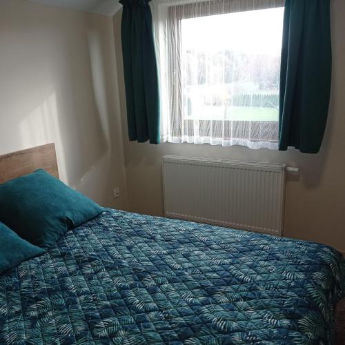 a bedroom with a bed with a blue comforter and a window at Ośrodek Wczasowy "Wczasy pod gruszą" in Biecz