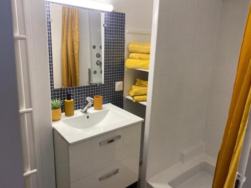 uma casa de banho branca com um lavatório e um espelho em Le cinéma em Soultz-sous-Forêts