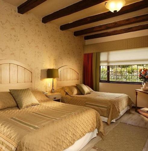 a bedroom with two beds and a window at Uzhupud Garden Hotel & Lodge in Paute