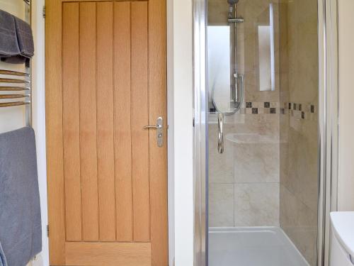 a bathroom with a shower and a toilet and a door at Hornbeam Cottage in Great Malvern