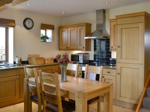 a kitchen with a wooden table and a clock on the wall at Hutter Hill Barn West in Silsden