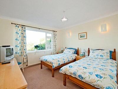 a bedroom with two beds and a tv and a window at Seacot in Runswick