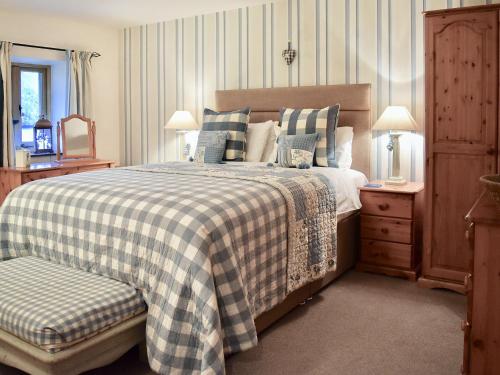 a bedroom with a bed with a checkered blanket at Barn Owl in Ipplepen