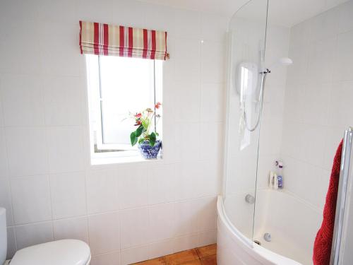 a bathroom with a tub and a toilet and a window at Greenbank Cottage in Hilgay